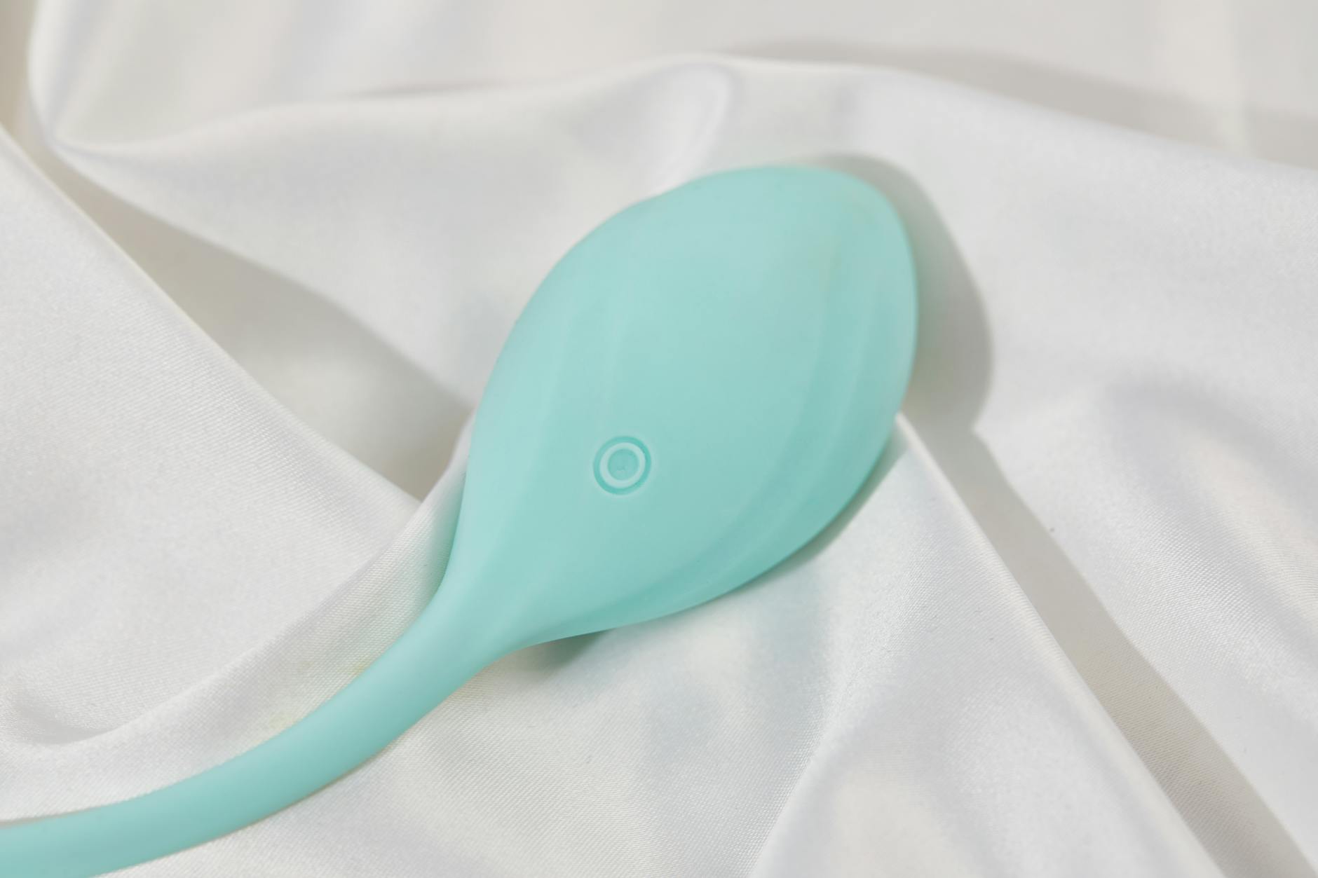 Vibromasseur bleu teal sur tissu de soie lisse blanc, parfait pour l'imagerie mode de vie pour adultes