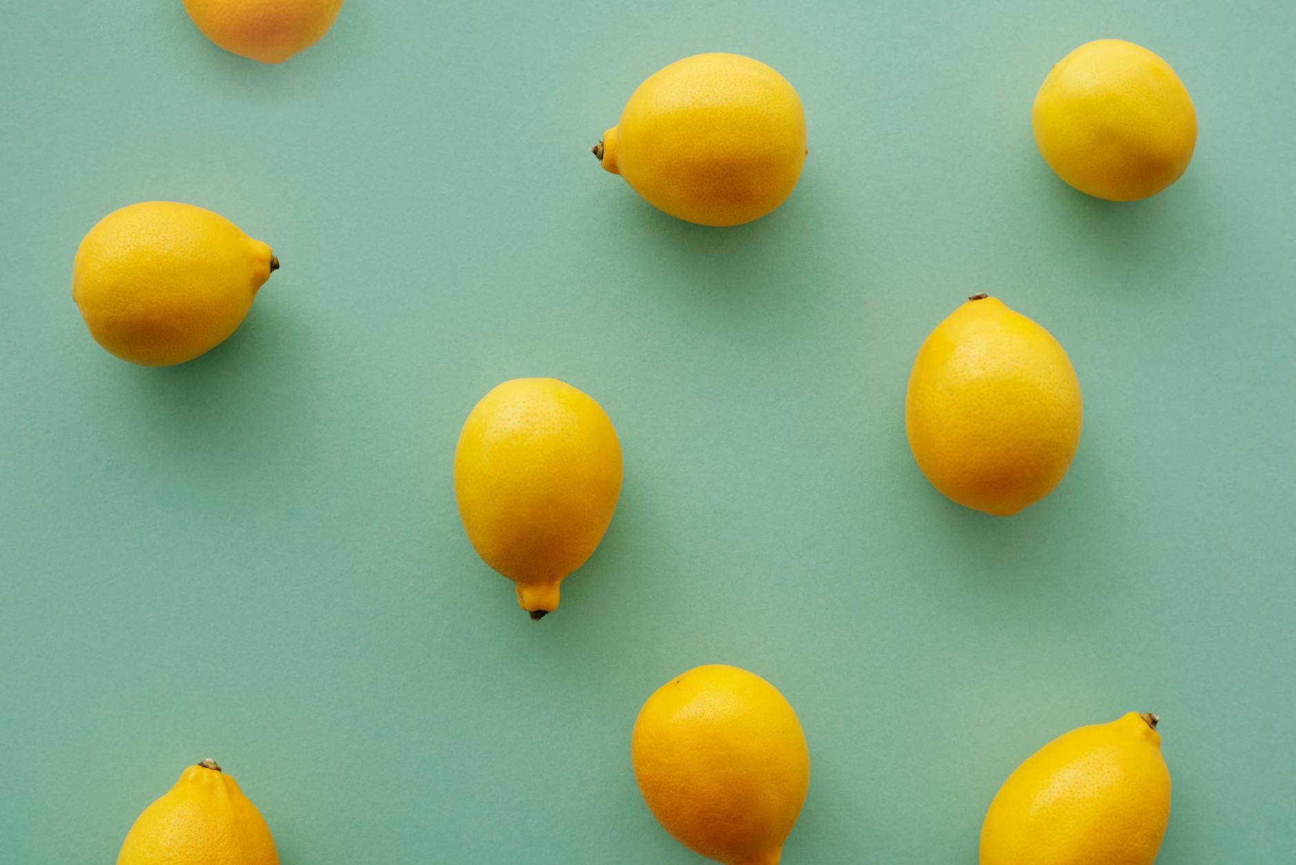 Bright yellow lemons arranged on a pastel green background, symbolizing fresh sensation and renewed pleasure in intimate relationships.