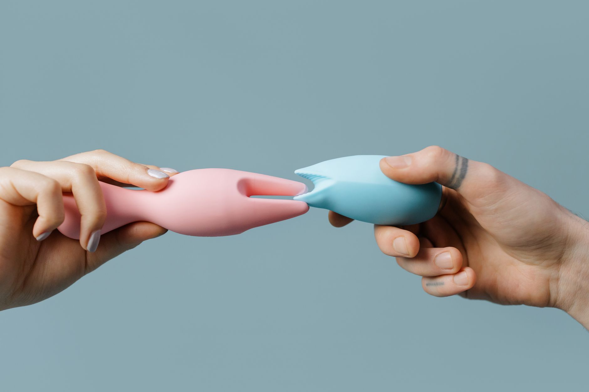 Close-up of hands holding a sleek blue vibrator against a purple background
