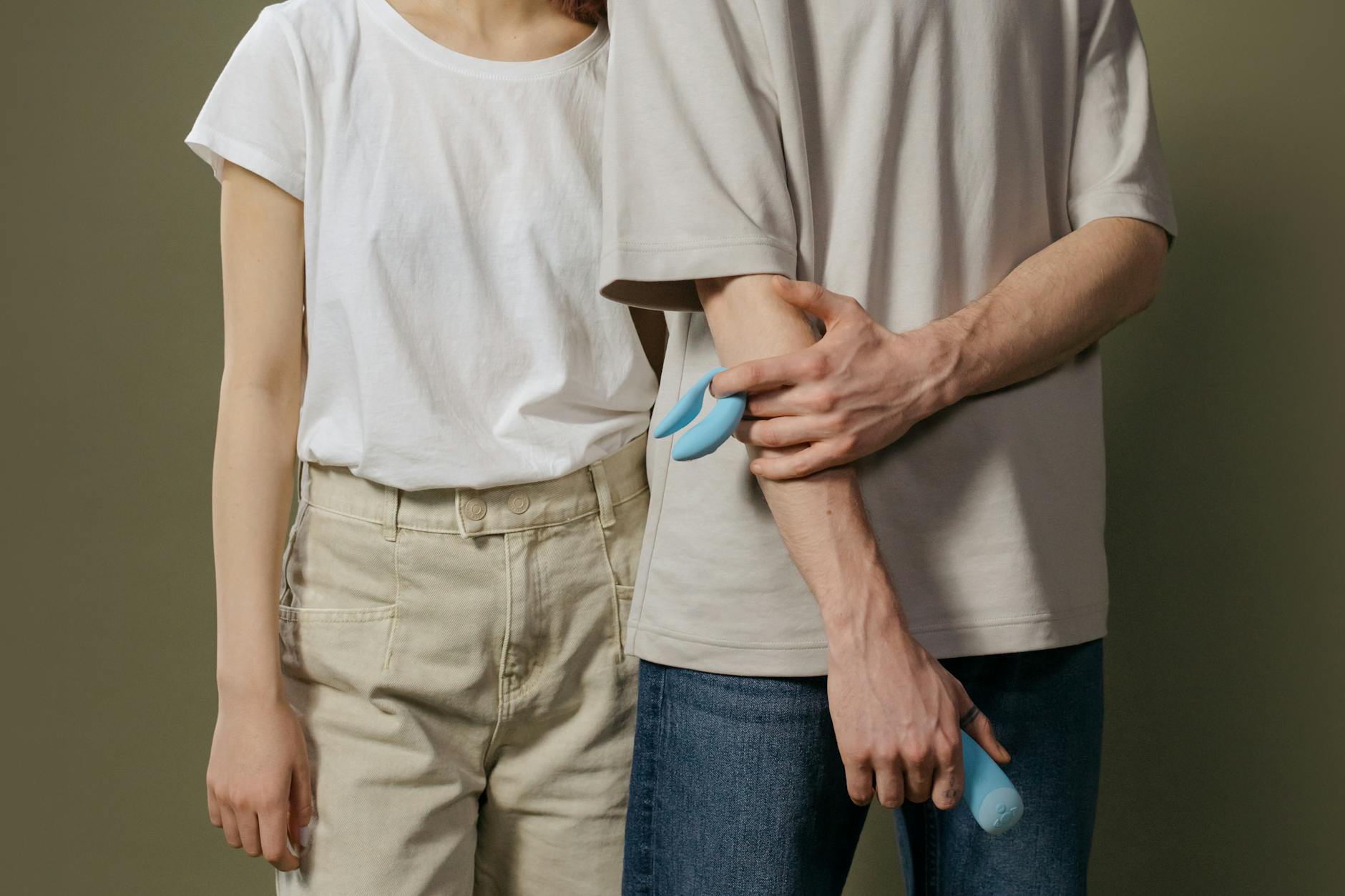 A hand holding a fresh lemon against a soft pink background, symbolizing the gentle approach needed for sensitive tissue